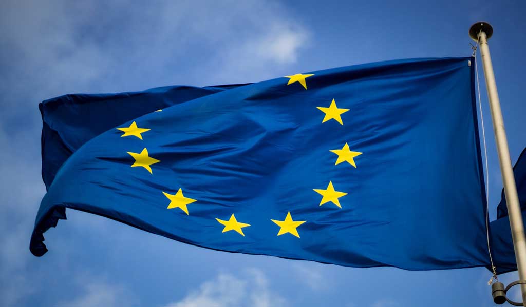 A European flag flying against a blue sky, Photo by Christian Lue on Unsplash