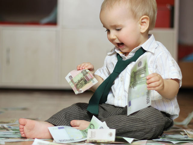 A toddler playing with a pile of cash he received as a holiday gift