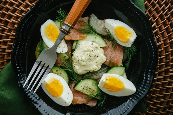  salad with hard-boiled eggs and smoked salmon in a black bowl