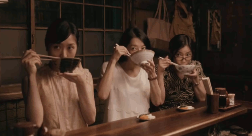 An animated gif of a scene from the movie 'Midnight Diner' of three women sitting at a Japanese pub eating noodles in sync.