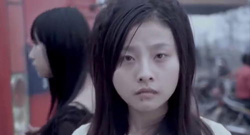 A close-up screenshot of a young woman staring intensely at the screen while her friend looks off at something else. From the Chinese independent film 'Here, Then'.