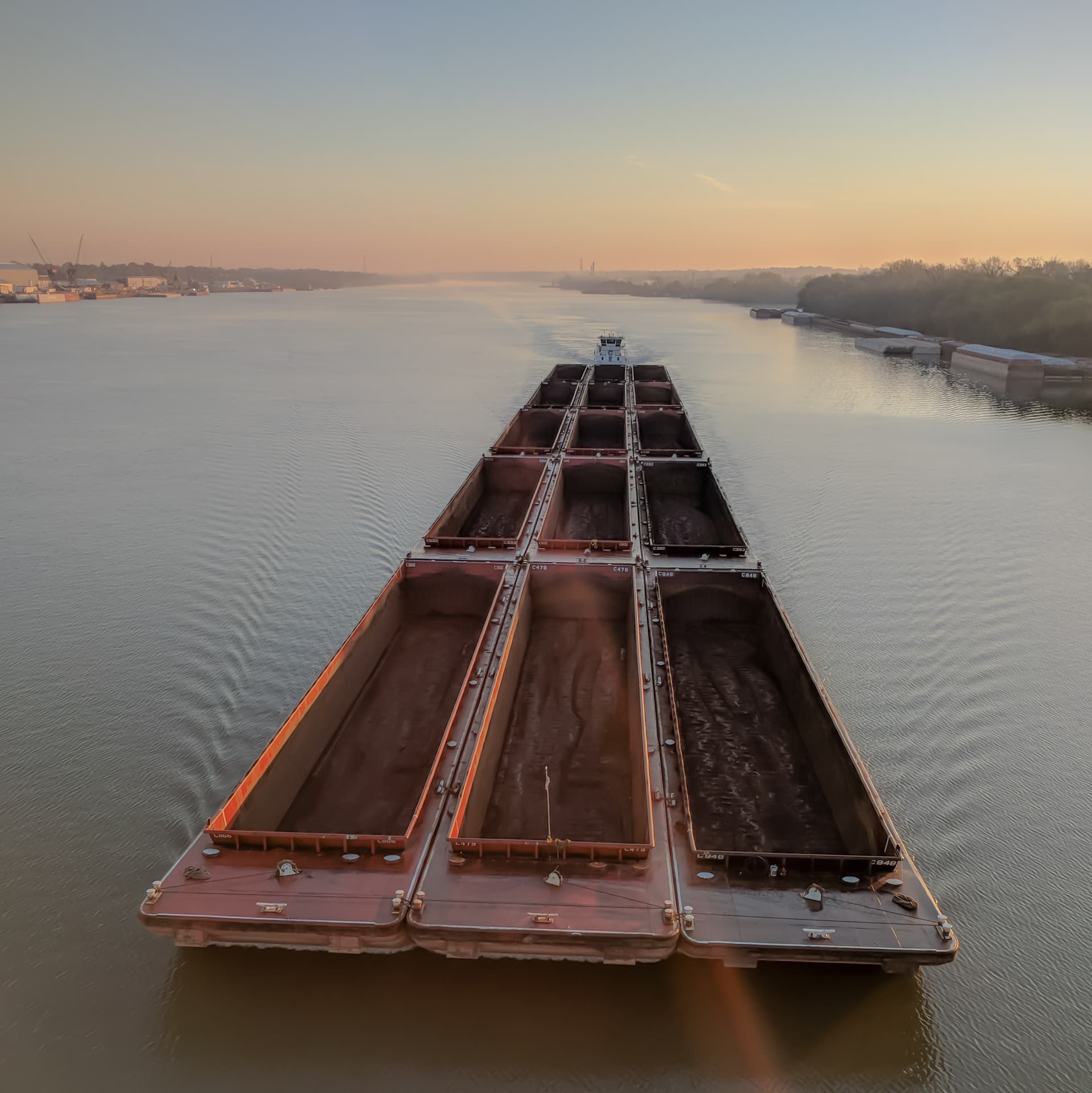 The view directly down towards an empty coal barge traveling west along the Ohio River at dawn.