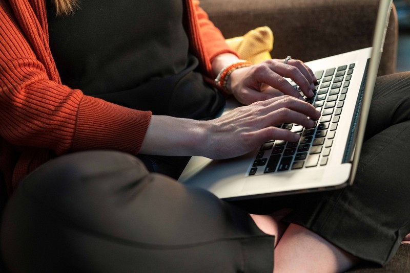 Sitting woman in red sweater typing on her laptop