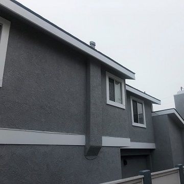 second picture of a grey painted stucco home with white painted trim