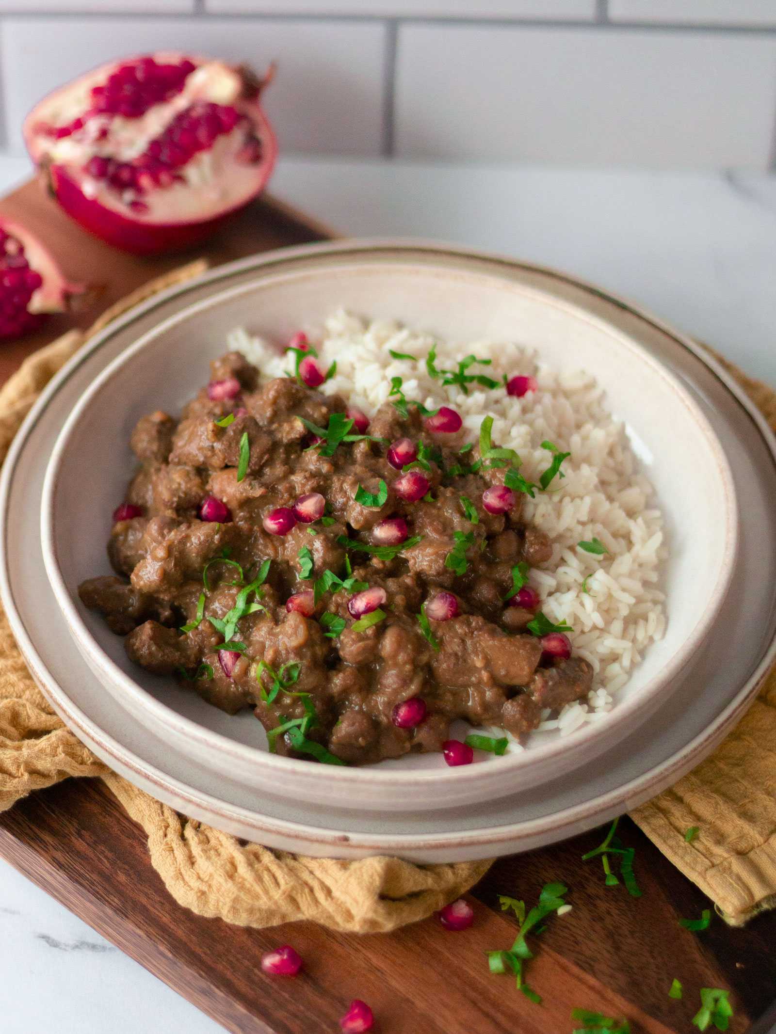 Fesnjan is a Persian dish, which in the provided image, is displayed in a white bowl topped with fresh pomegranate seeds. This sweet and sour stew has chicken thighs cooked in a spiced walnut and pomegranate molasses. Its rich tangy flavour will surely awaken your taste buds. 