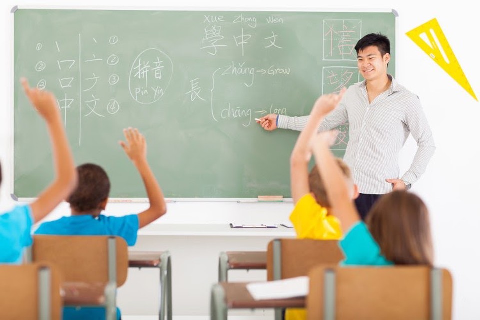 A teacher points to a chalkboard in front of a group of students.