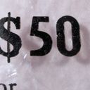 Dollar sign with digits five and zero printed in black on a clear plastic bank bag.