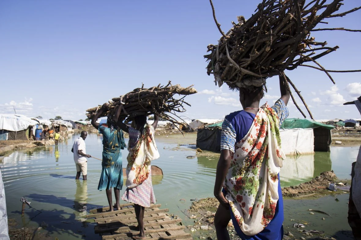 Women carry firewood back to their homes through contaminated flood water in the displacement camp on the UN base in Bentiu, the capital of oil-producing Unity State in South Sudan.