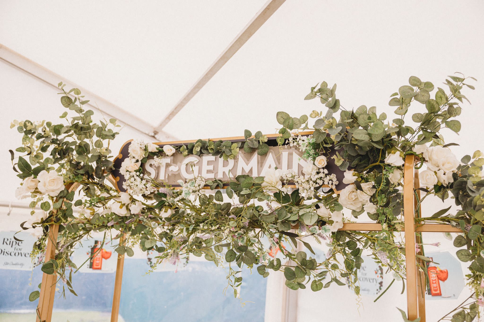 flowers atop st Germain gin stand at wedding ceremony