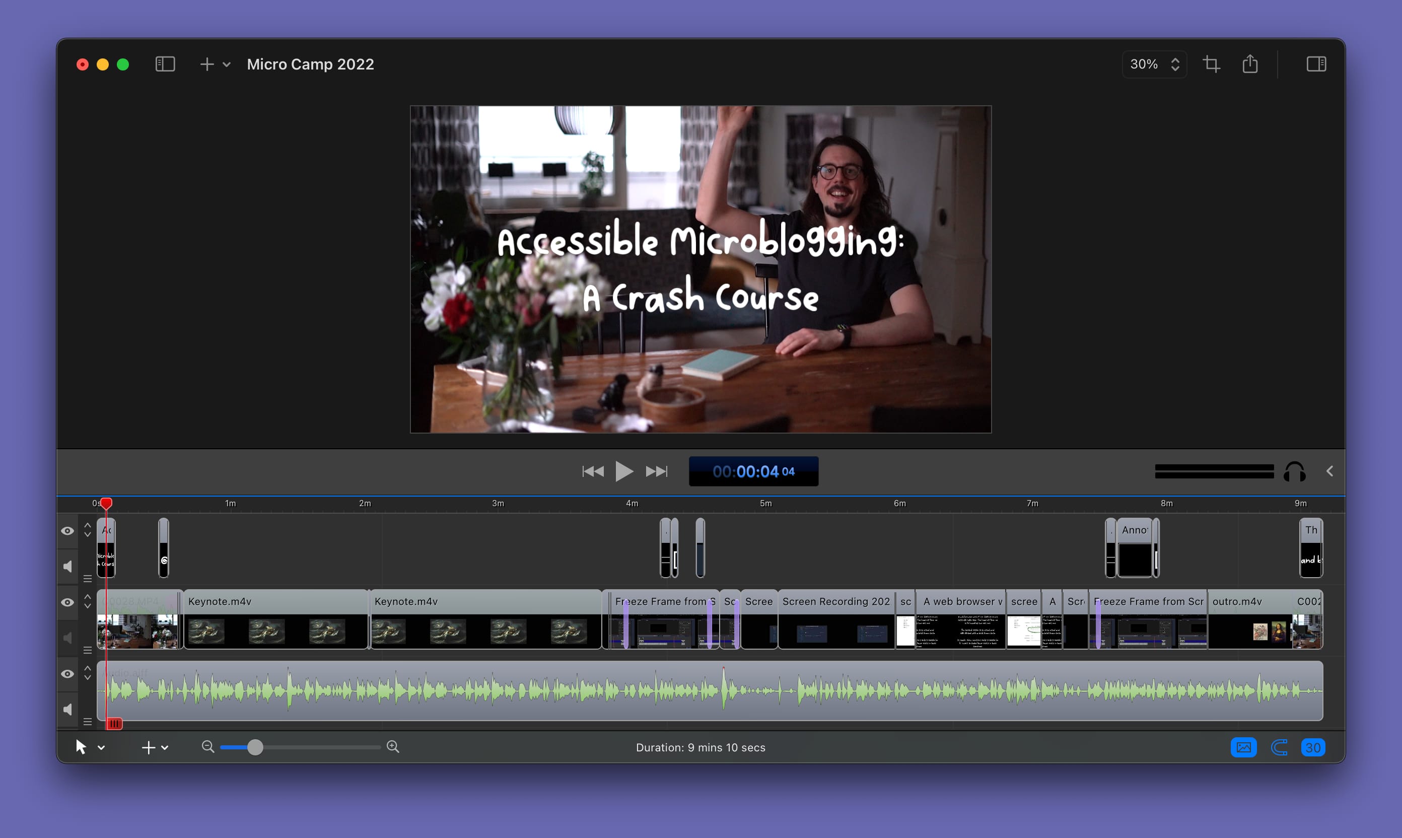 Video editing software with an open project named Micro Camp 2022. The scrubber is set to around 4 seconds, and the video preview shows a happy guy sitting at a table raising his hand in a salutation. The title is set in a playful font and reads Accessible Microblogging: A Crash Course.