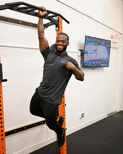 Basit Adeyinka, a physiotherapist at Integral, hanging from a chin-up bar with one hand