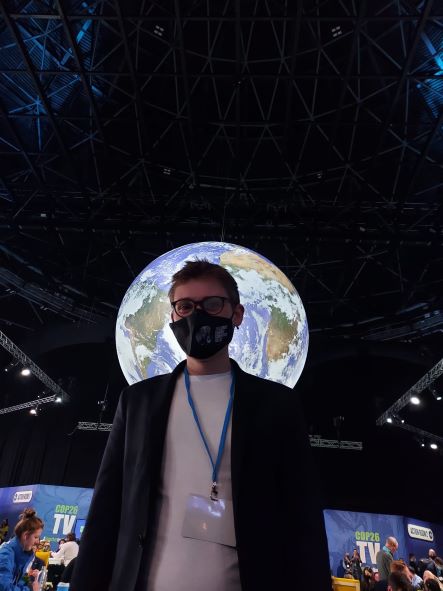 Man wearing a mask and standing in front of a globe at COP26