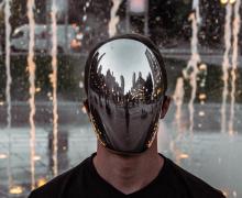 A man wearing a reflective, faceless mask