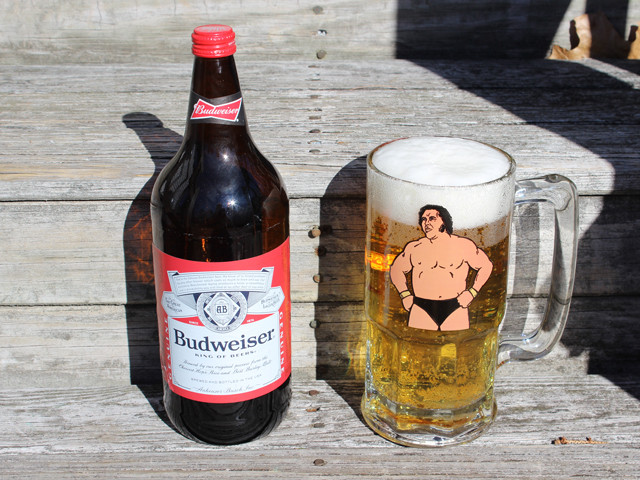 An Andre the Giant Beer Stein that is full of beer, next to a 40oz bottle of Budweiser