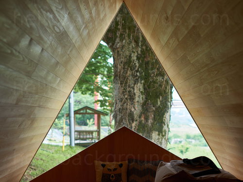 Wooden seating unit with small pillows framed in a triangle shaped window with garden view Google Meet background