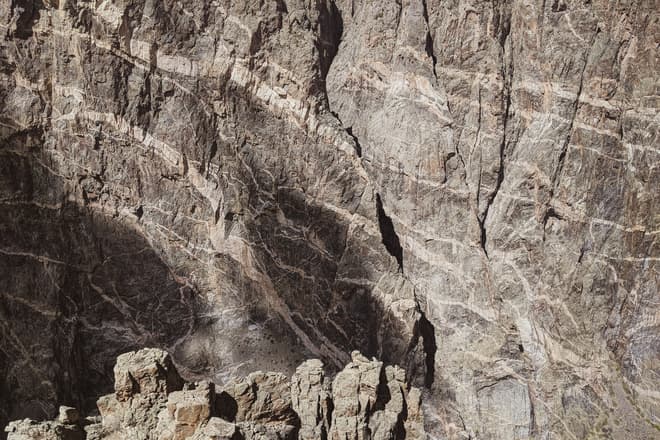 The wall of the deep purple rock of the Black Canyon of the Gunnison, shot through with intrusions of white granite.