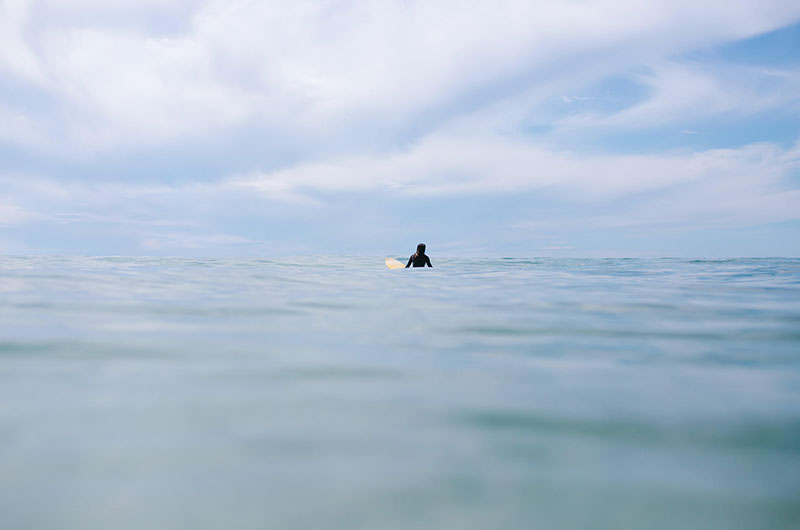 Photo from the water with a surfer on the horizon