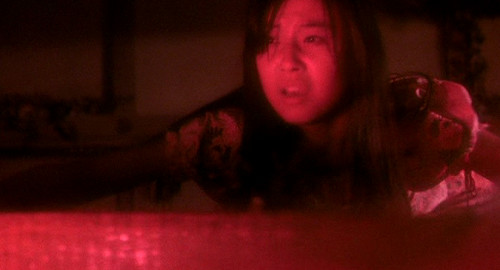 A screenshot from the Japanese film 'House' of a girl named Fantasy (played by Kumiko Ohba) struggling on a tatami mat that is floating on bloody water.