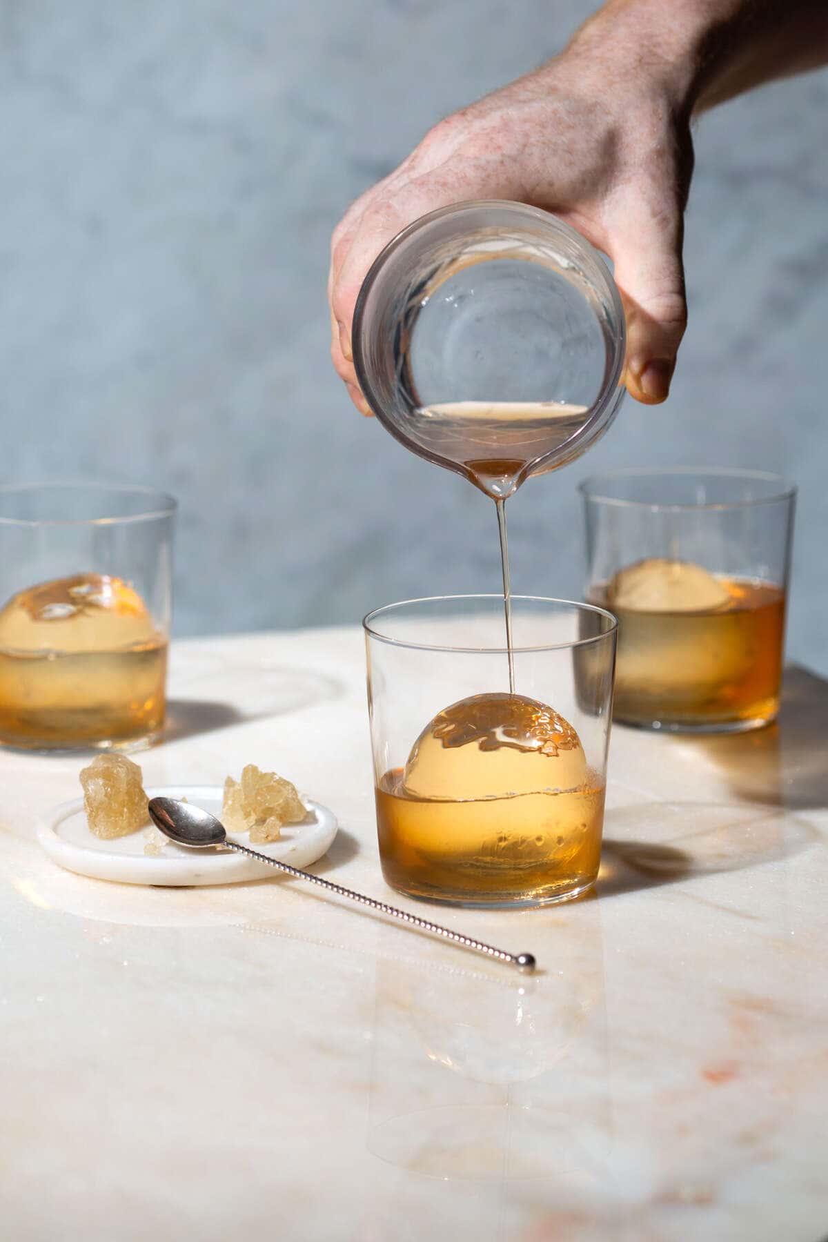 whiskey being pored onto large ball of ice