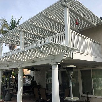 white painted pillars holding a white painted deck that is covered by a white pergola