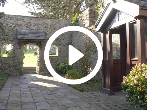 Stone country house courtyard with wooden porch entrance next to flower bushes and with natural light Google Meet background