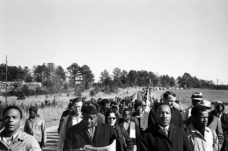 Black and white photo of MLK marching in Selma. Beside him are Andrew Young, Ralph Abernathy, and John Lewis.