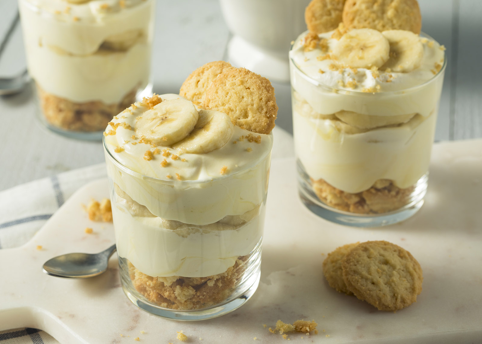 glass bowls of banana pudding sitting on a wooden table