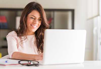 A woman smiling while using a laptop computer