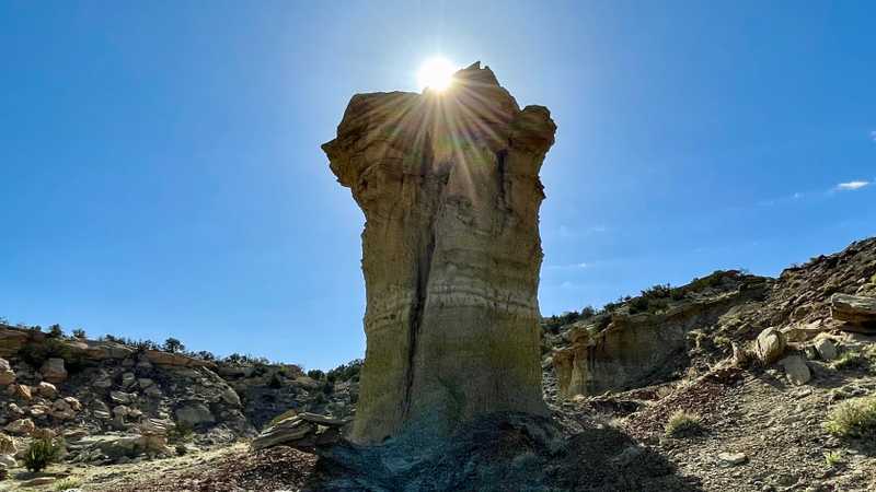 The sun shines brightly over a hoodoo