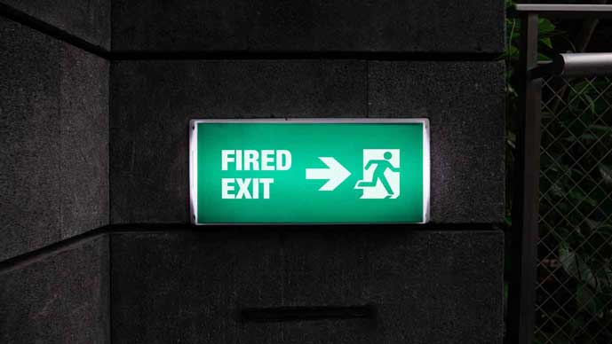 Photo illustration of an exit sign at night. The sign says “Fired Exit.”