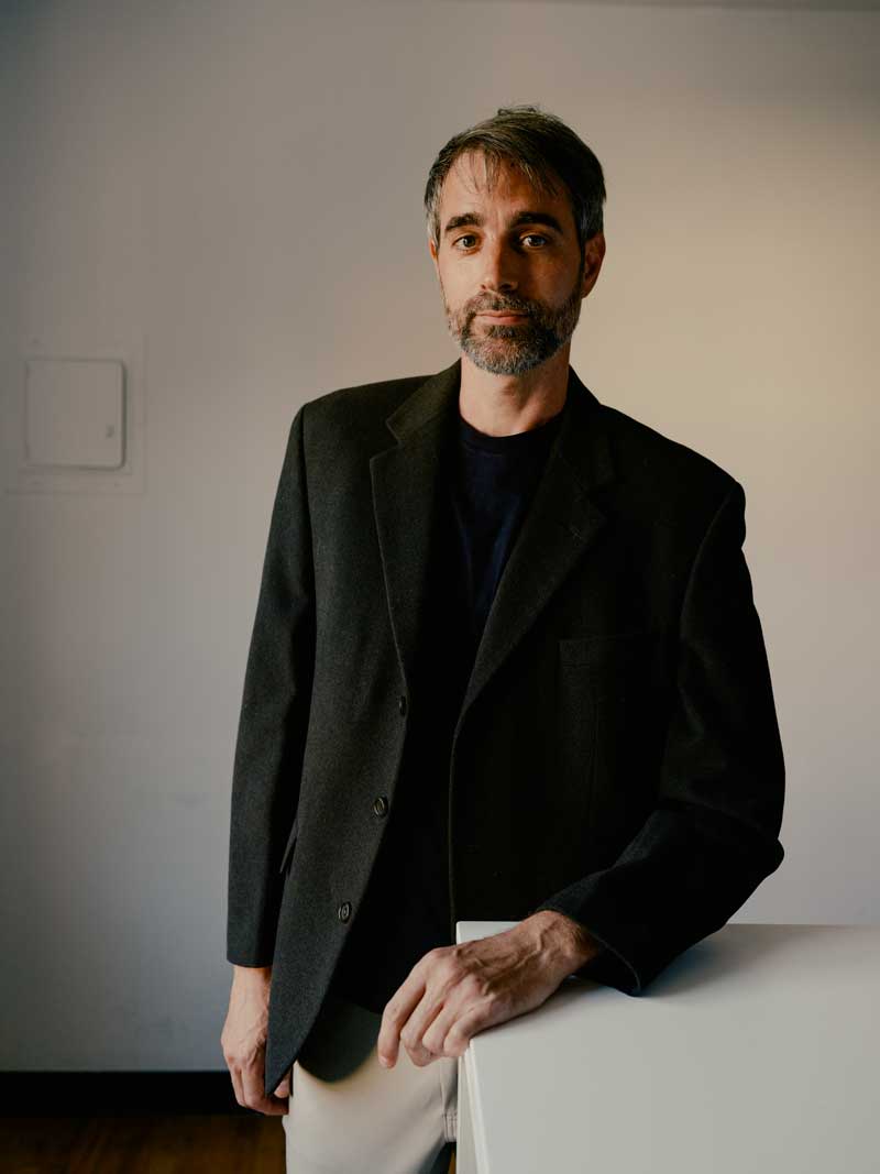 Photo of a man wearing a green blazer, looking directly at the camera with a slight smile.