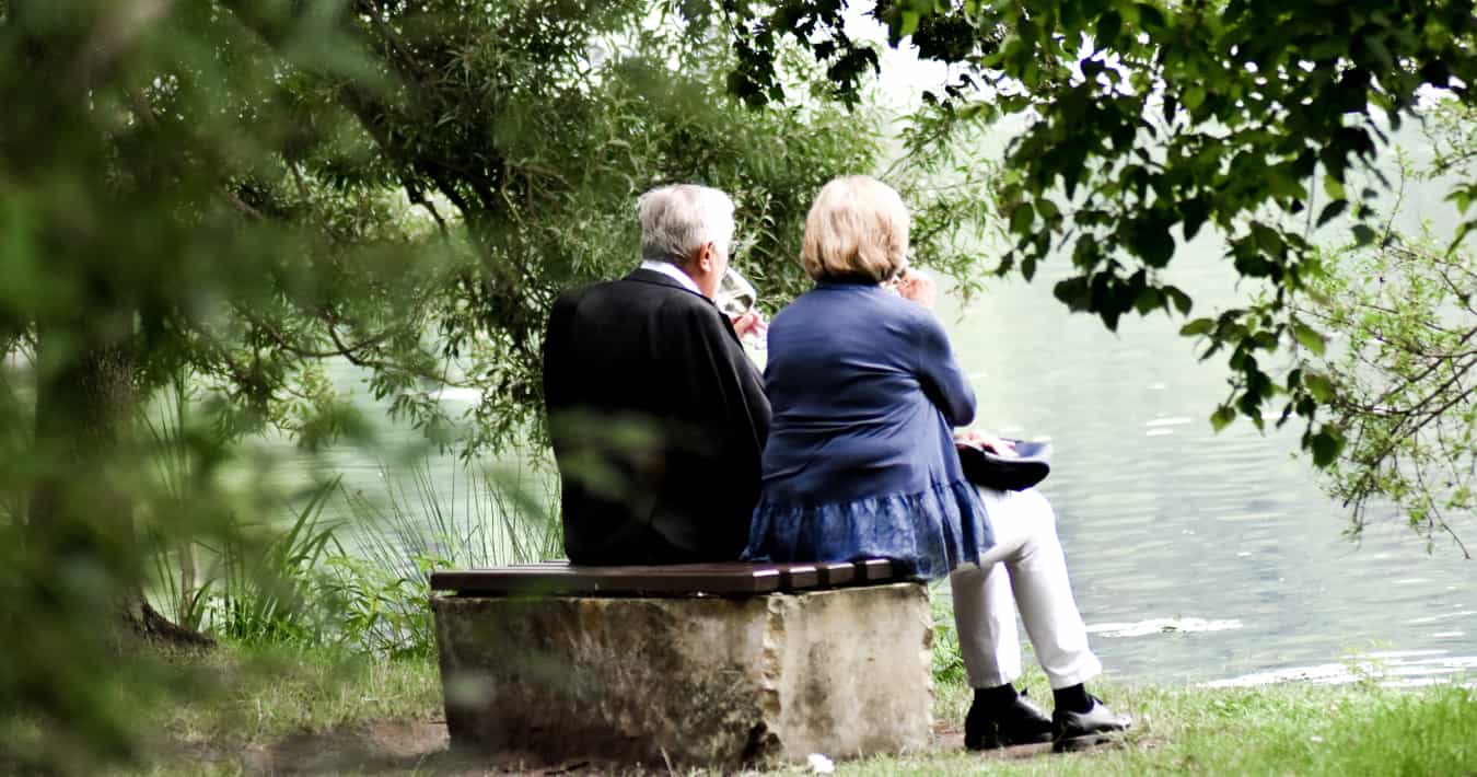 Elderly couple sitting together looking at the water