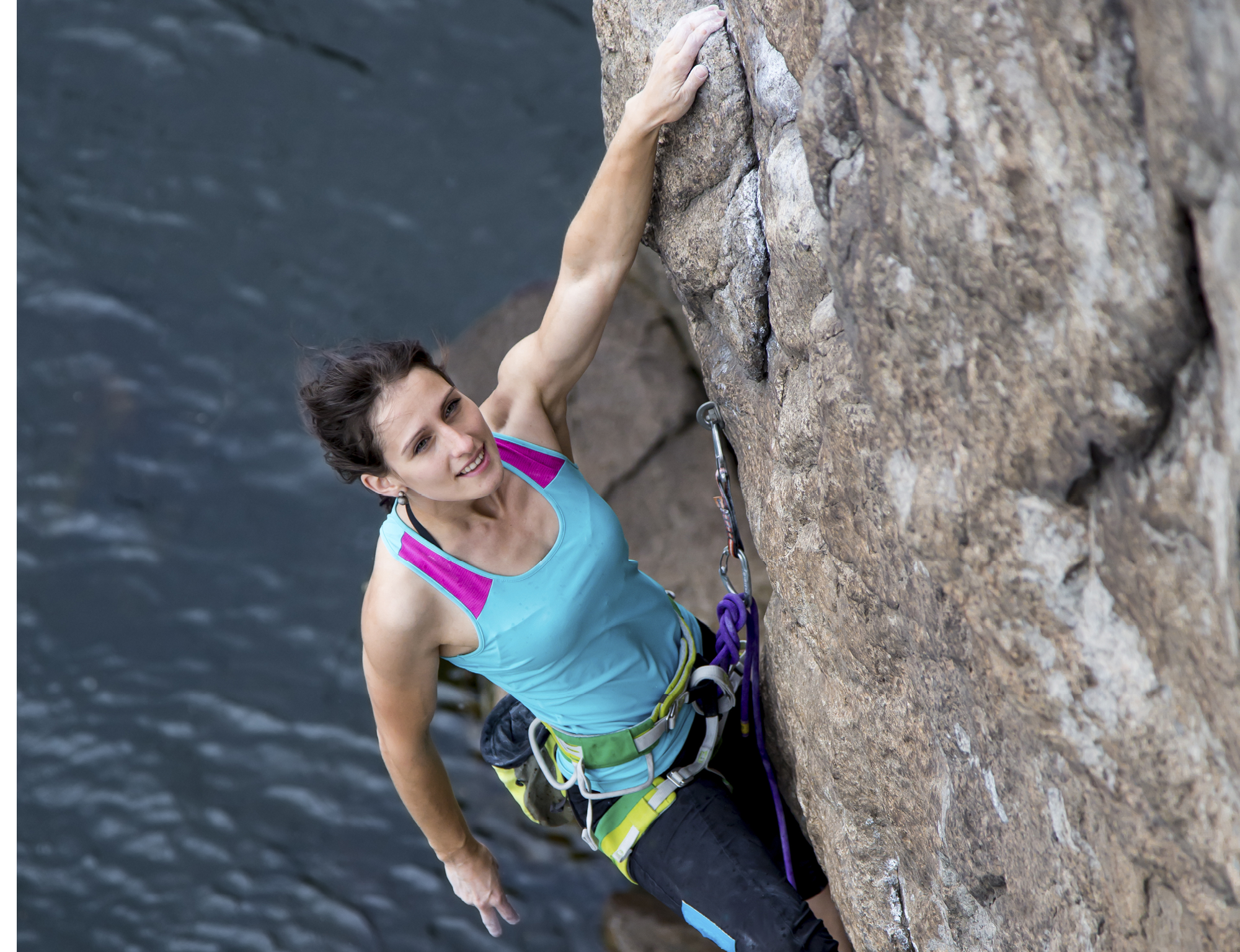 Female extreme climber hangin over the deep water Female extreme climber hangin over the deep water
