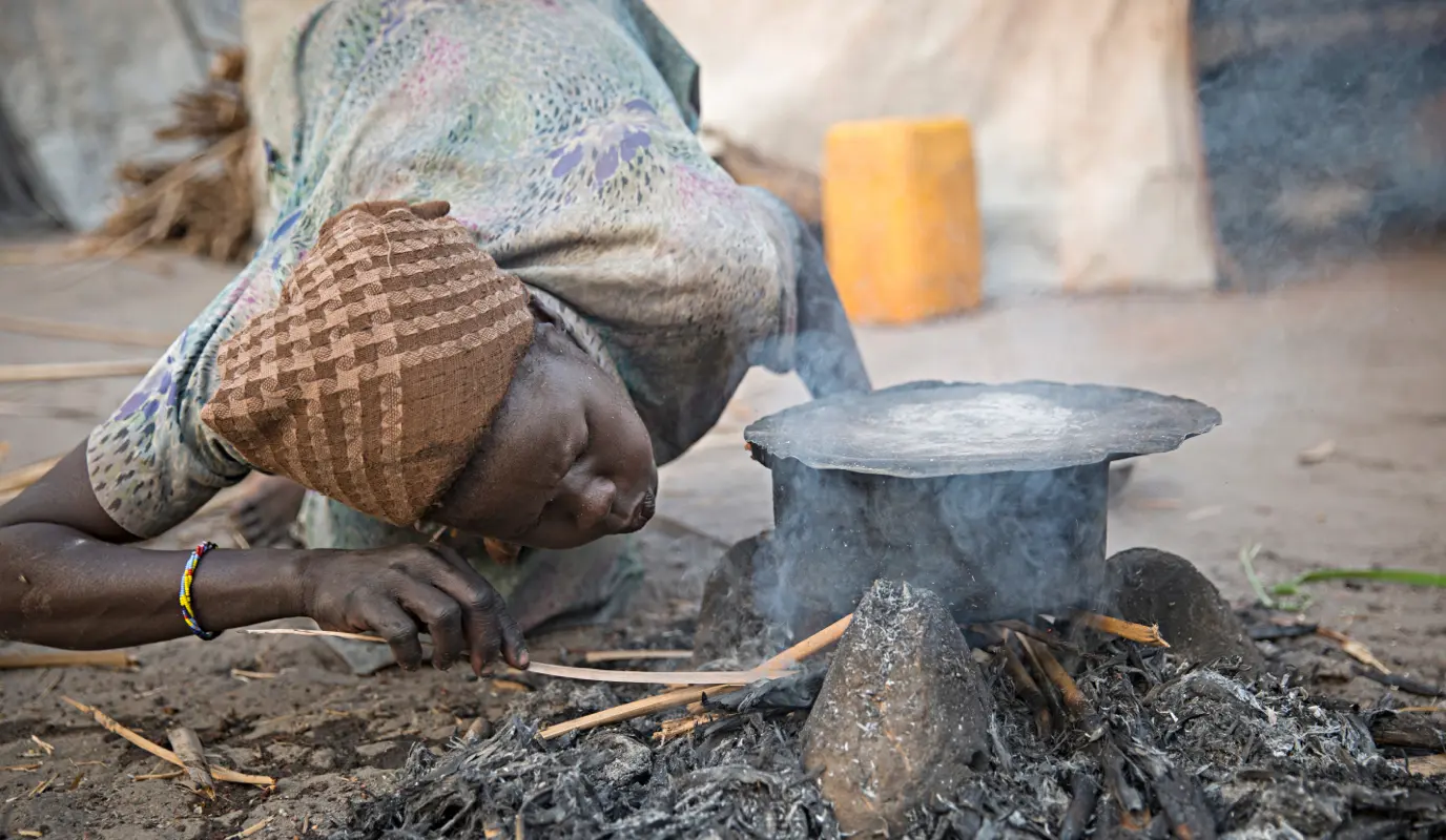 A woman starts a cooking fire at the temporary settlement built on Kok Island in the swamps of Leer County, Unity State, South Sudan.