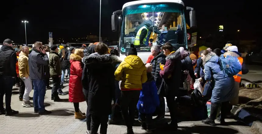 Families seeking refuge from conflict in Ukraine board buses at a reception center in Przemysl, Poland
