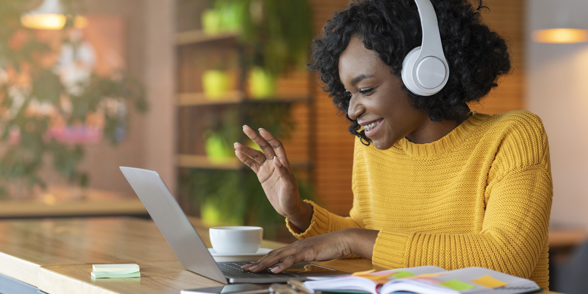What are the best data analytics certification programs on the market? A woman sitting at a table smiling at a laptop, wearing headphones