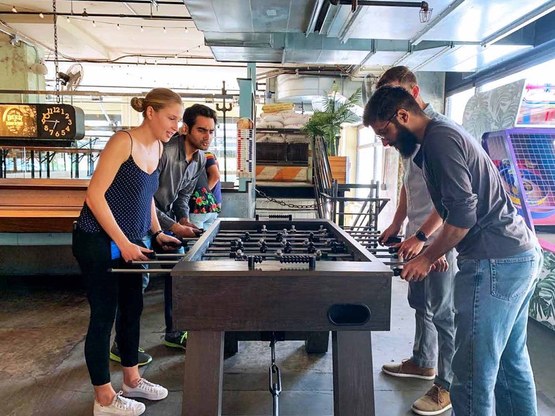 A group of interns unwind after work with a game of foosball