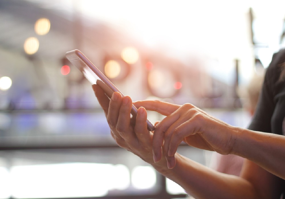 Close up of women's hands holding smarthone. Her watching sms, message, e-mail on mobile phone in coffee shop. Blurred background.