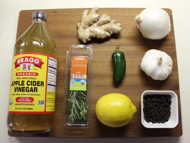 An assortment of ingredients to make fire cider, including Apple Cider Vinegar, Jalapeno Pepper, Garlic, Ginger, Lemon, Onion, Pepper and Rosemary