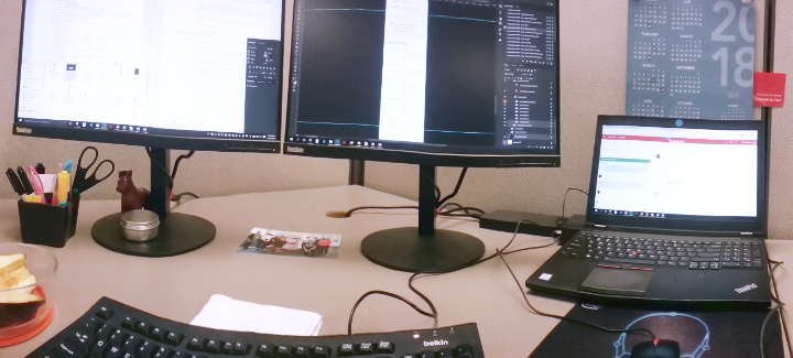 My brown cubicle at Cardinal Health, with 2 monitors and 1 laptop displaying complex workflows.