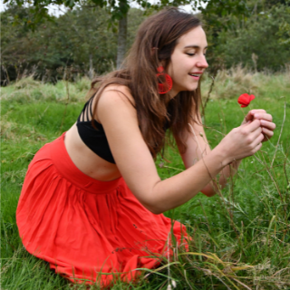 Griet, met rode rok, plukt een rode bloem