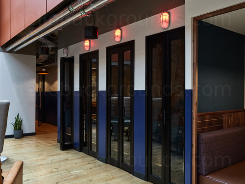 Modern shared workspace featuring private study booths with glass doors and orange vacancy lights Skype background