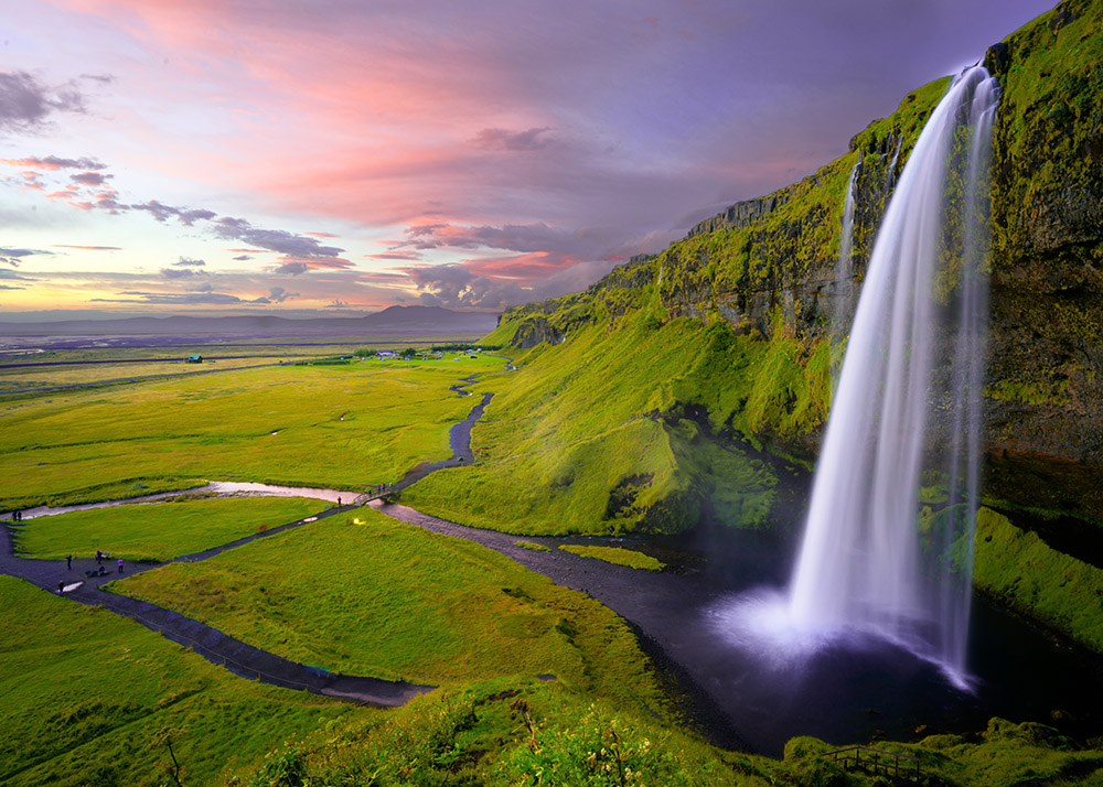 green grass, pink sky, and tall waterfall in iceland