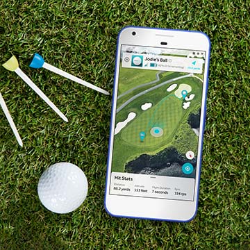 Several golf tees and a golf ball sitting on the grass next to a smartphone that displays a golfing app