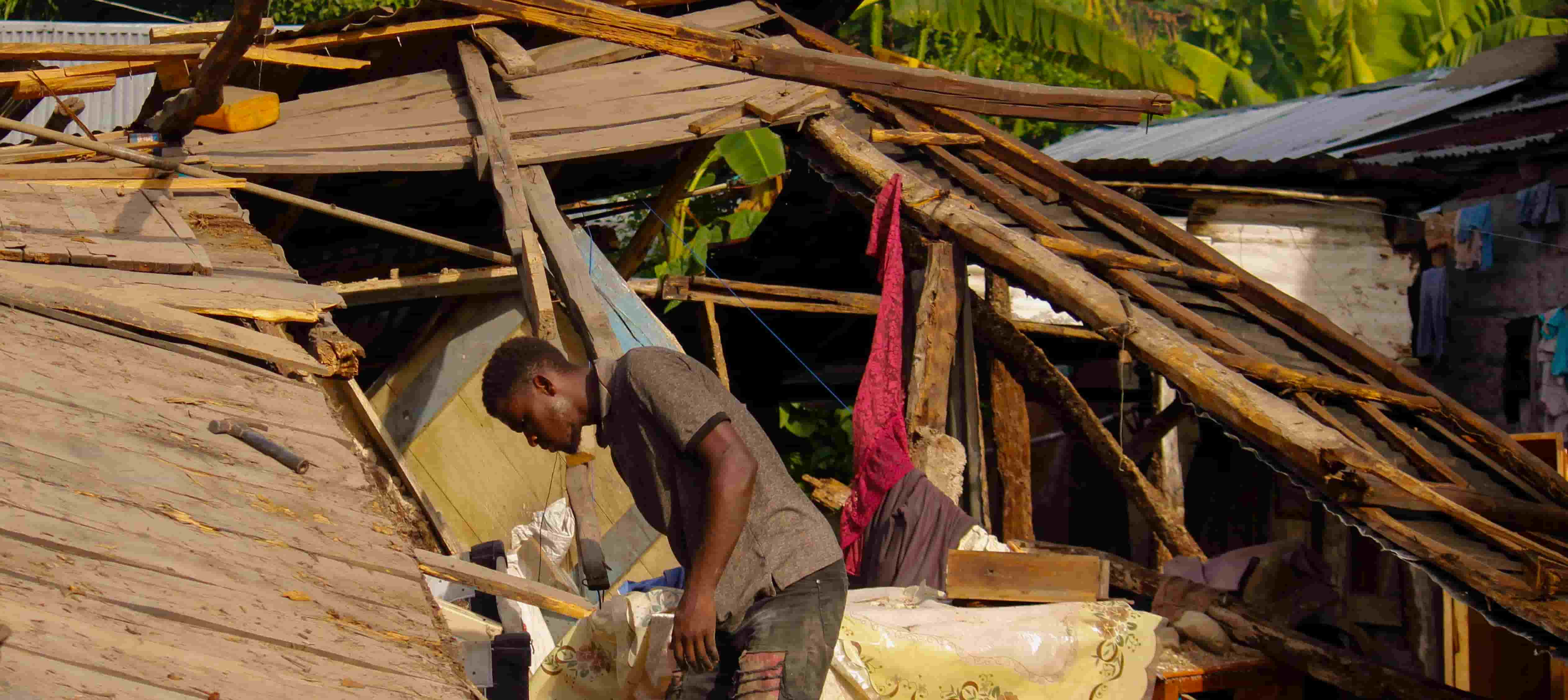 A man searches for goods in his destroyed house