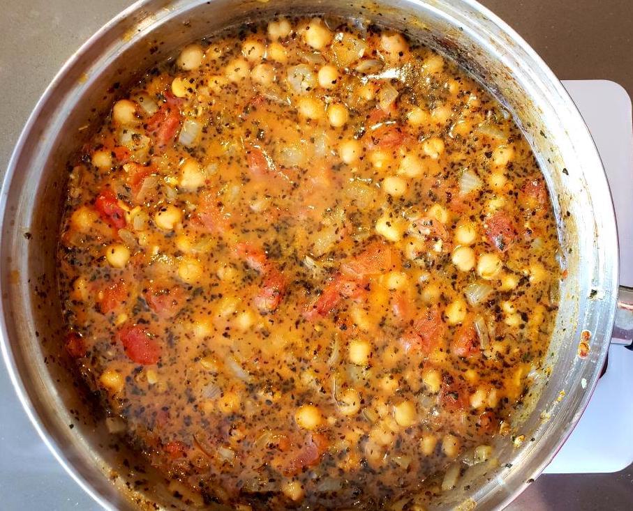 Pan of chickpea curry with tomatoes and basil