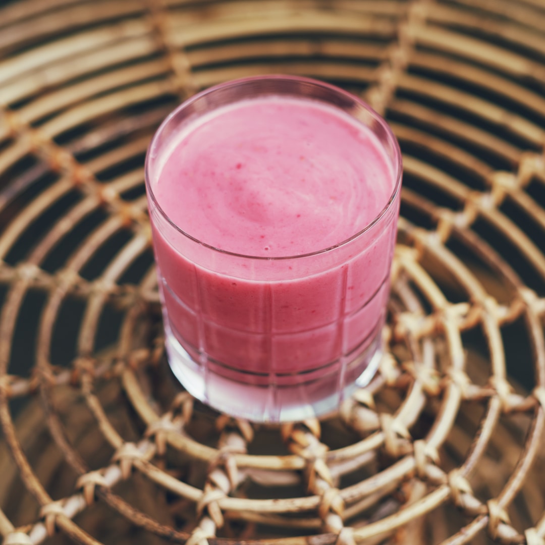 A delicious looking, pink smoothie in a old fashioned glass.