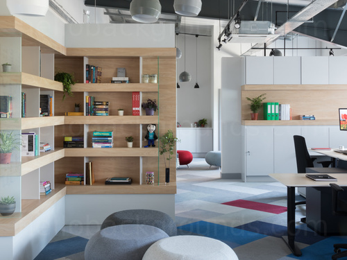 Modern open workspace featuring artistic floor design under wooden shelves with trinkets next to corner desk and chair   Skype background