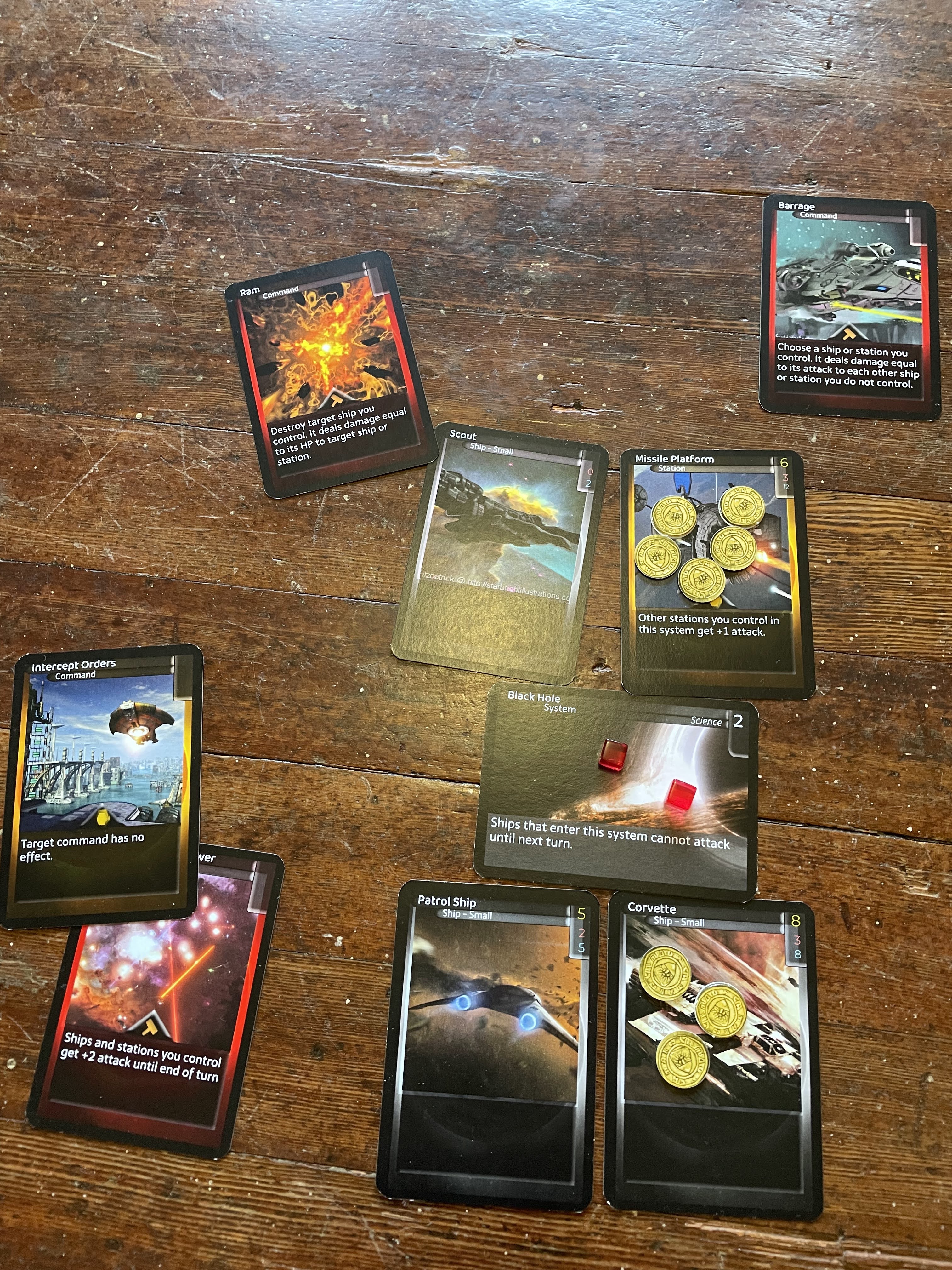 The four ship card involved in combat, plus a number of command cards placed around them to highlight what is going on. Damage counters are placed on one of the cards.