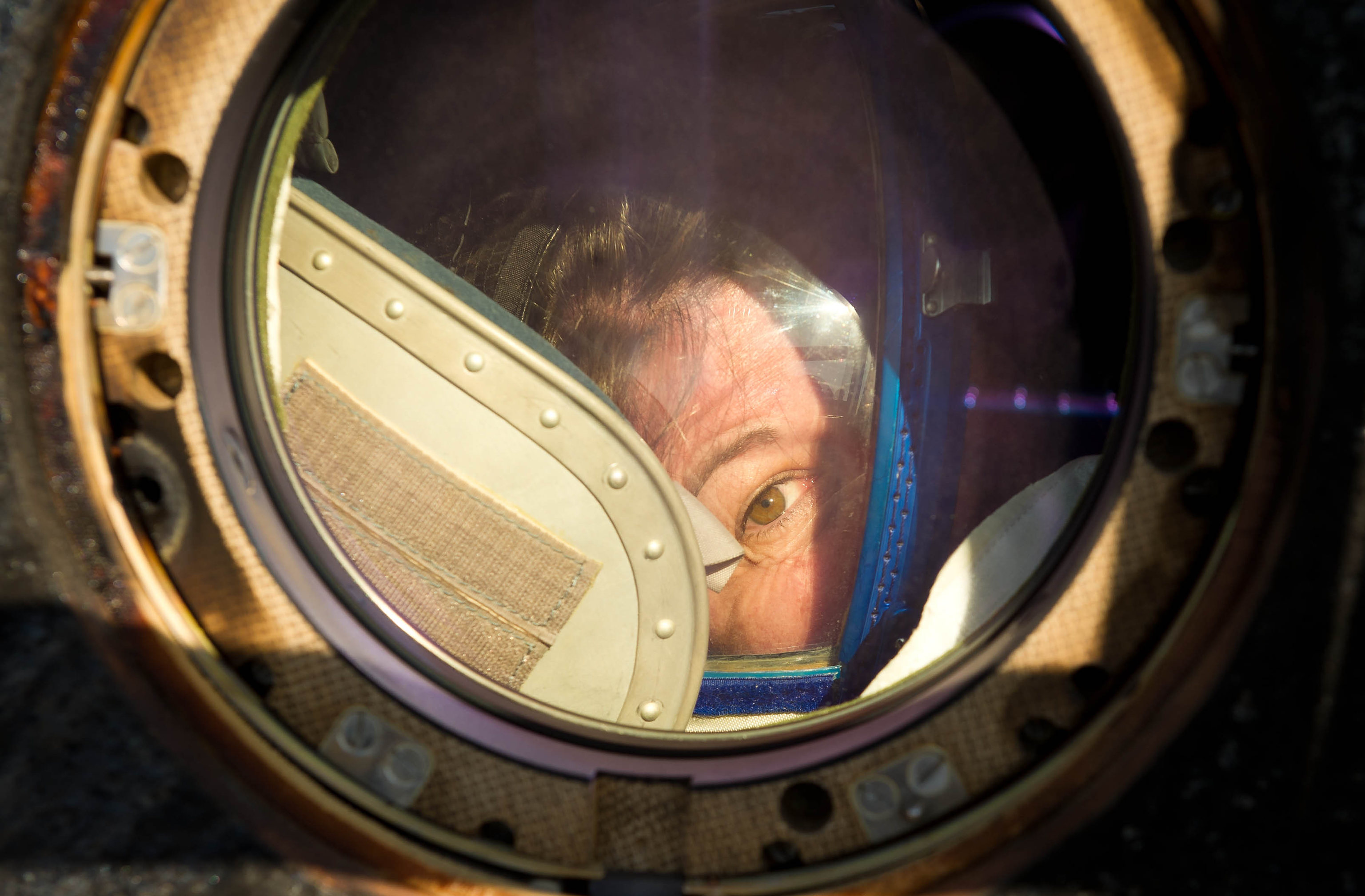 un astronauta guarda fuori dal finestrino della Soyuz appena atterrata